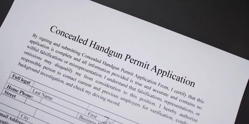concealed-handgun-permit-application A close-up shot of a "Concealed Handgun Permit Application" form lying on a dark surface, showing the title and the personal information fields at the bottom.