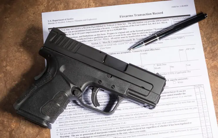 Handgun and pen resting on an ATF Firearms Transaction Record