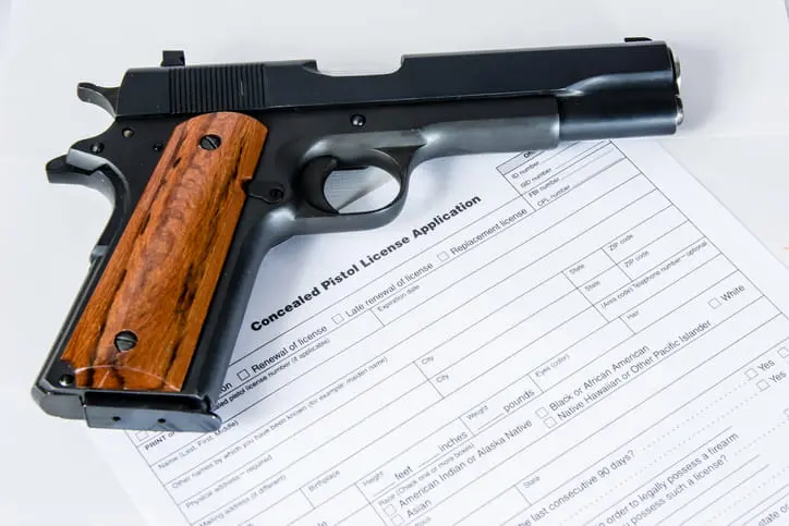Handgun with wooden grip resting on a Concealed Pistol License Application form